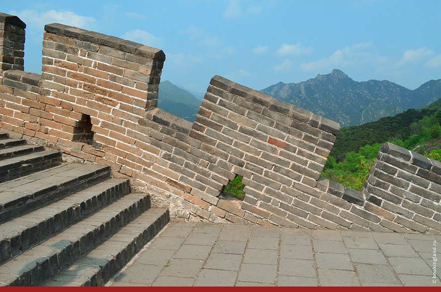Крутые ступеньки и бойницы Великой Китайской стены. На горизонте горы.