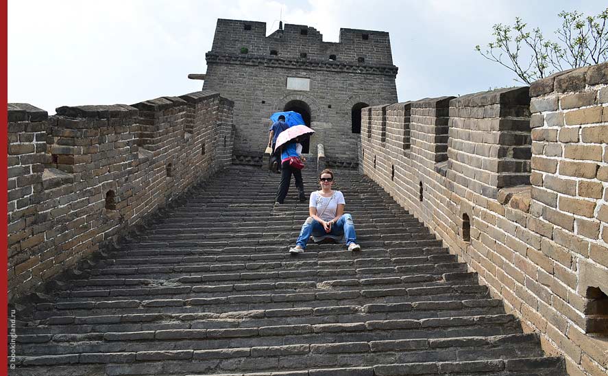 Крутой подъем по ступенькам Великой Китайской стены. Туристы укрываются зонтиками от жаркого солнца.