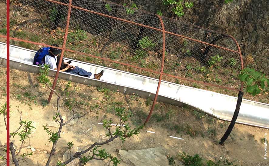 Турист тормозит джойстиком на спуске с Великой Китайской стены на тоббогане